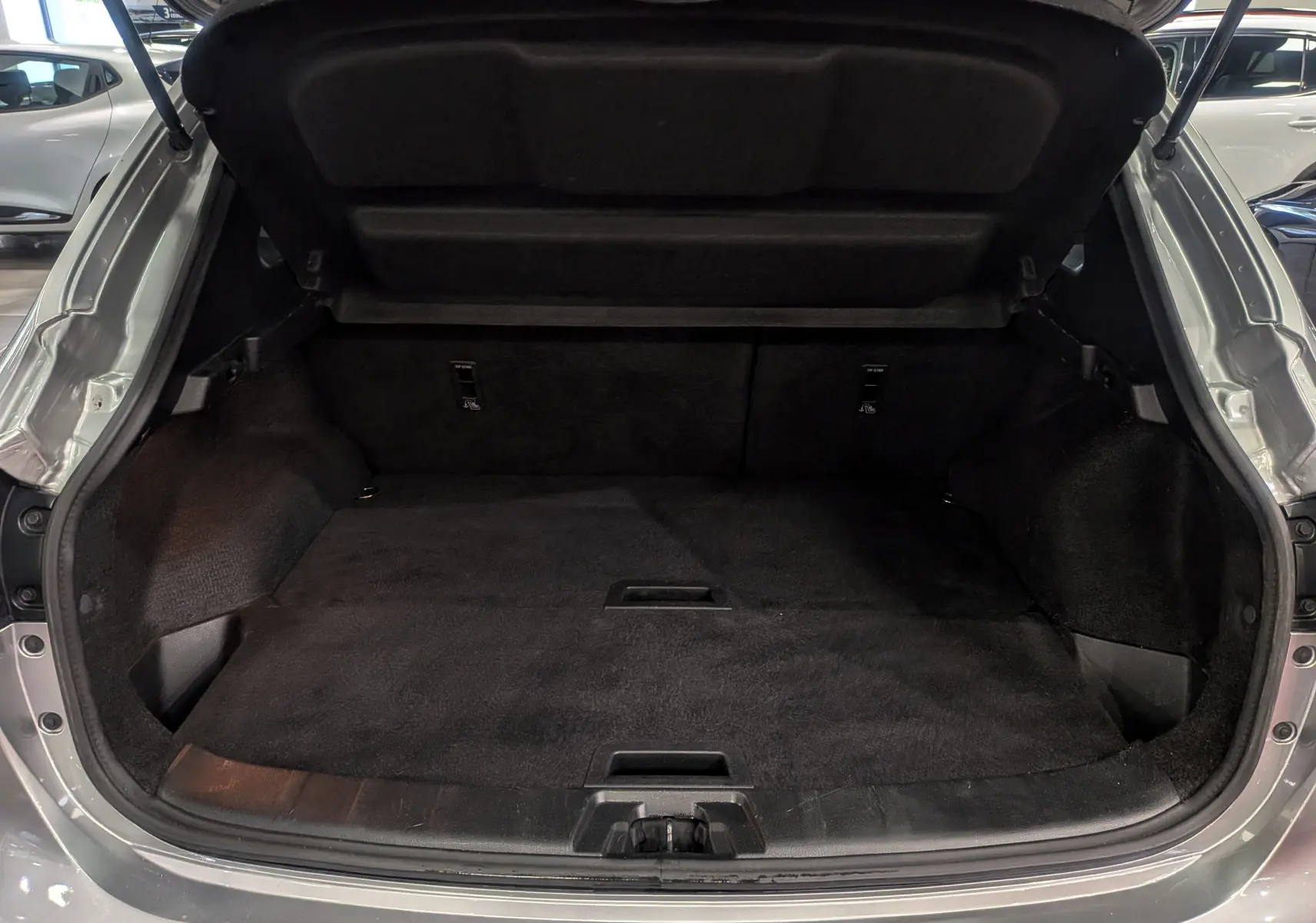 Coffre ouvert d'un Nissan Qashqai gris perle 2018, vue arrière montrant un espace de chargement propre et spacieux.