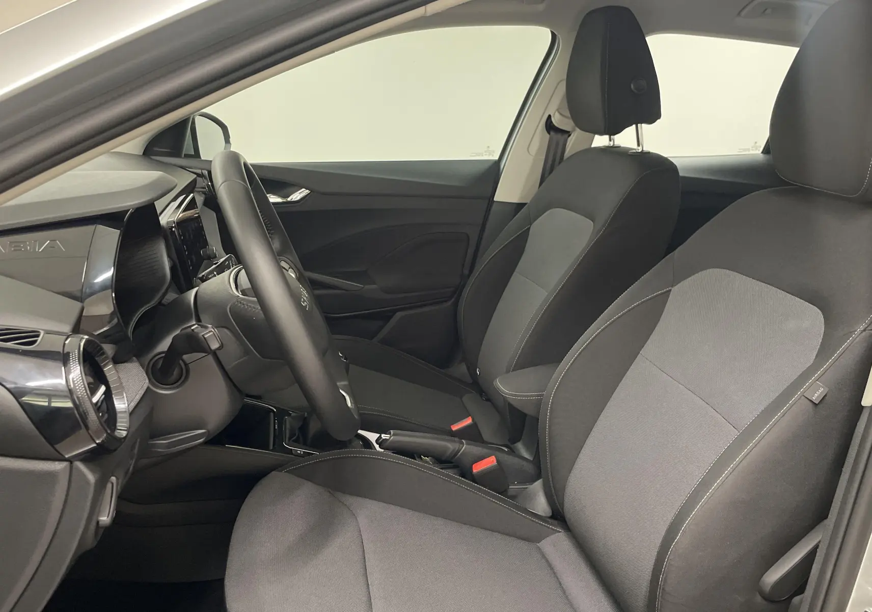 Intérieur avant de la Skoda Fabia gris argent, sièges tissu bicolore et tableau de bord moderne côté conducteur.