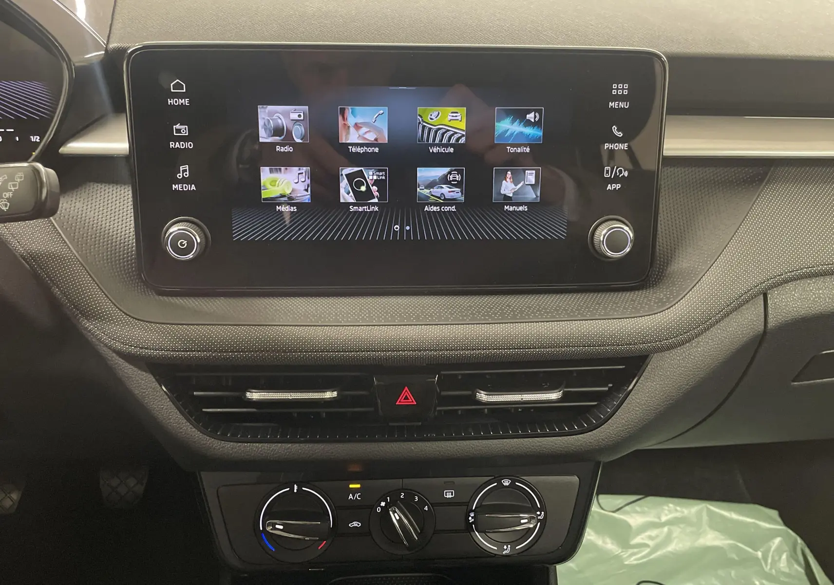 Tableau de bord de la Skoda Fabia 2025 avec écran tactile central et commandes climatisation visibles en intérieur noir.