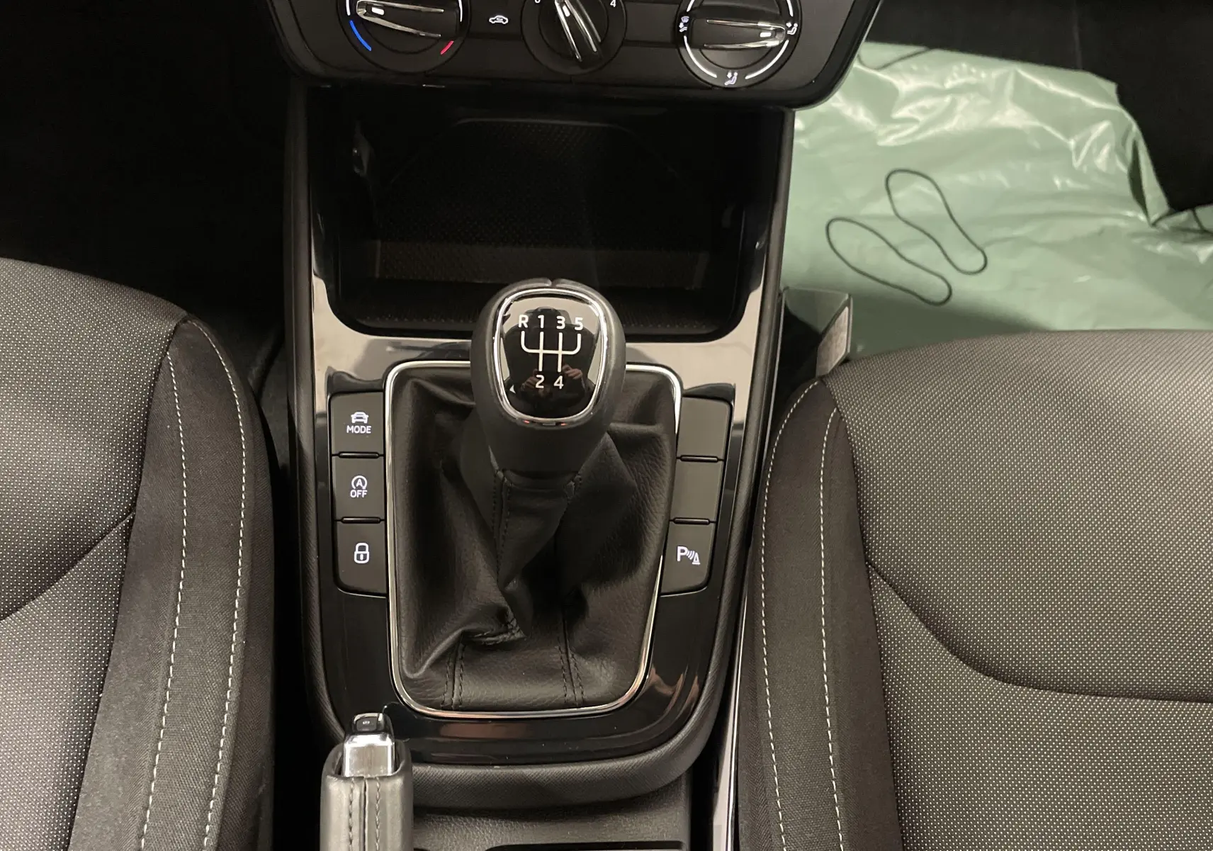 Vue rapprochée de la console centrale d'une Skoda Fabia gris argent, mettant en valeur le levier de vitesse manuel et les sièges noirs.