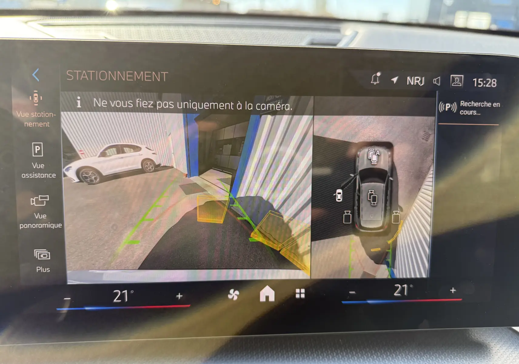 Vue caméra 360° du BMW X1 blanc mineral en stationnement, affichage écran intérieur avec guidage de trajectoire.