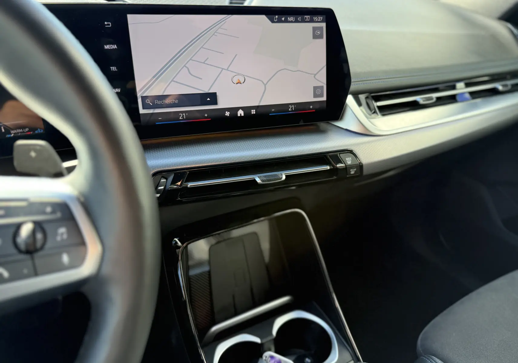 Vue intérieure côté conducteur du tableau de bord et écran tactile de navigation du BMW X1 blanc Mineral 2025.