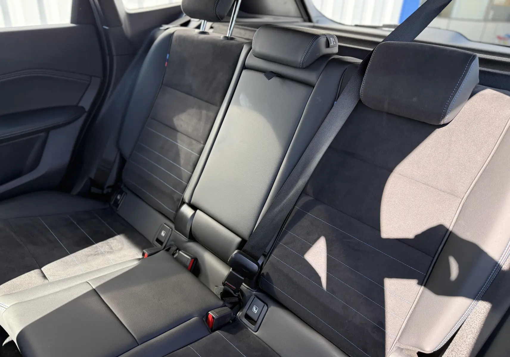 Vue intérieure des sièges arrière en cuir noir avec surpiqûres bleues du BMW X1 20D M Sport 2025.