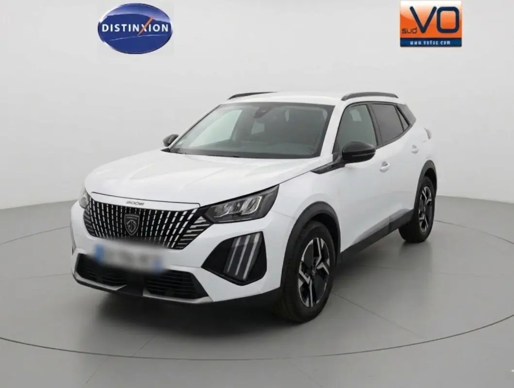 Peugeot 2008 blanc en 3/4 avant droit, avec barres de toit et jantes alliage 17 pouces visibles.