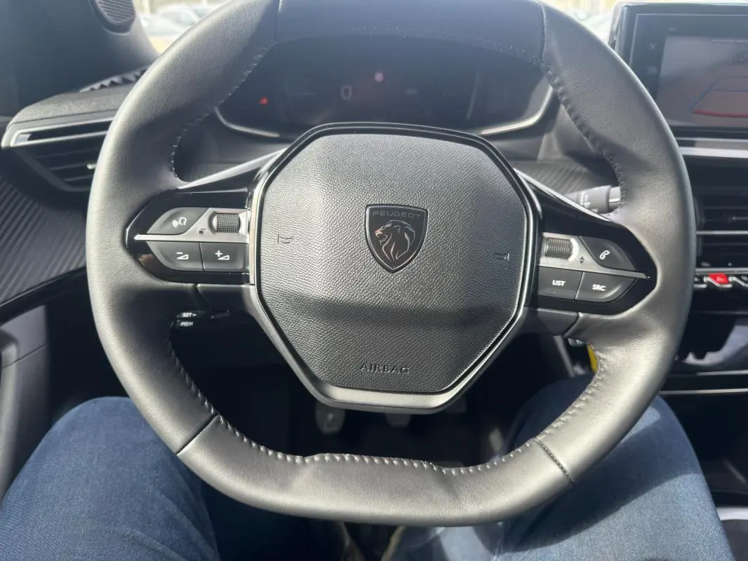Vue rapprochée du volant noir de la Peugeot 2008 2024, avec commandes intégrées et logo lion central.