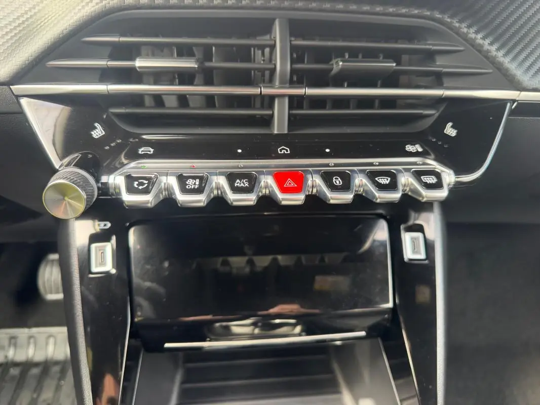Vue rapprochée du tableau de bord noir du Peugeot 2008 2024, avec rangée de boutons argentés et écran tactile éteint.