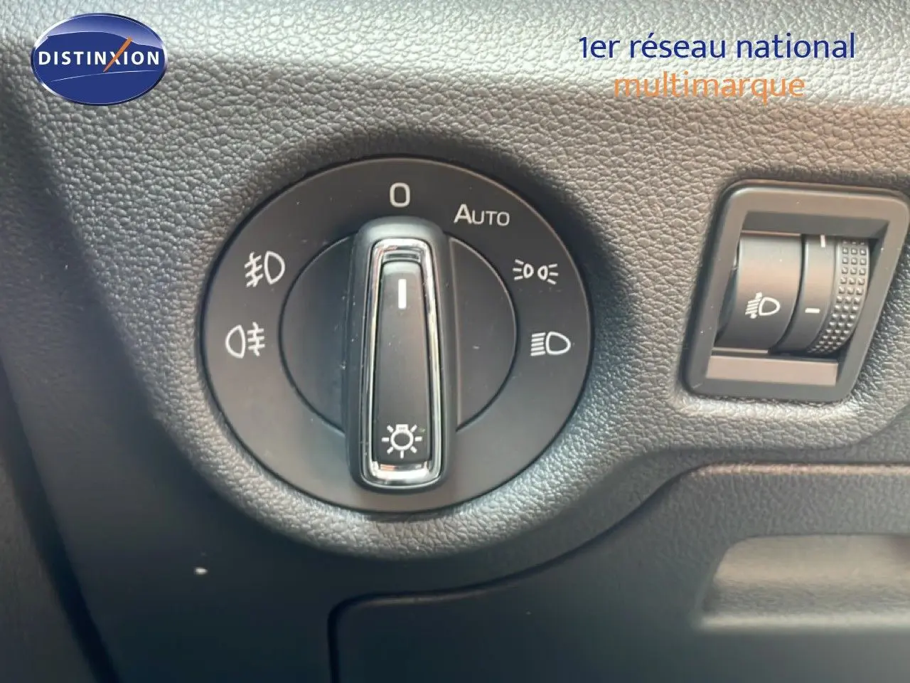 Gros plan sur la commande des phares du Skoda Scala blanc glacier, avec molette de réglage et bouton d'intensité lumineuse.
