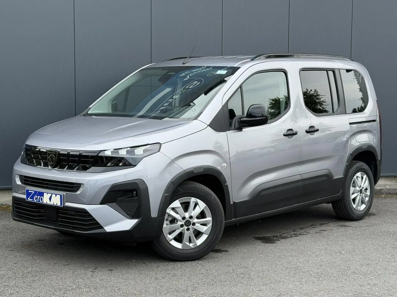 Peugeot Rifter gris acier en 3/4 avant droit, avec jantes alu 16 pouces et portes latérales coulissantes.