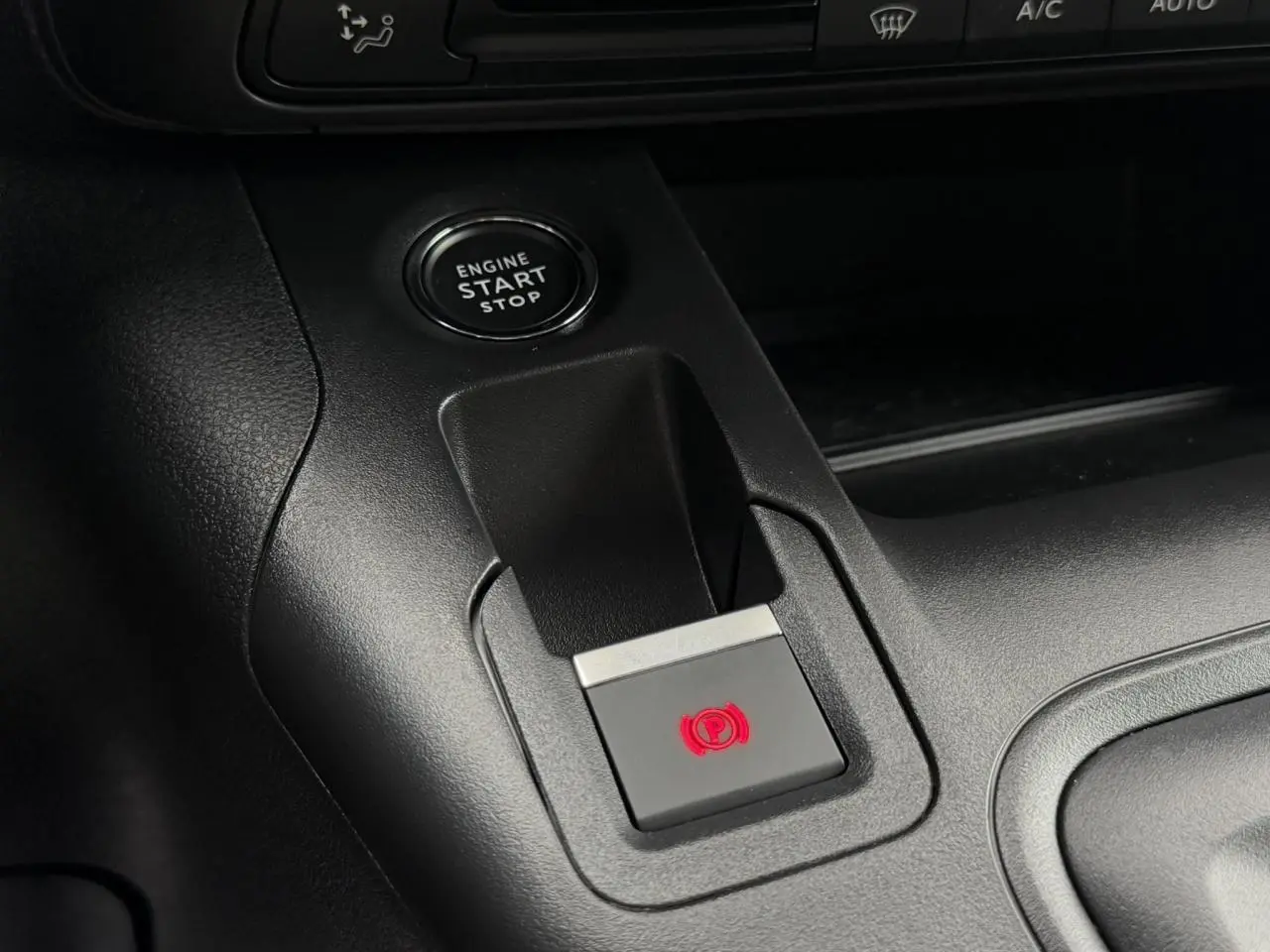 Gros plan sur le bouton de frein de stationnement électrique et démarrage moteur du Peugeot Rifter gris acier.