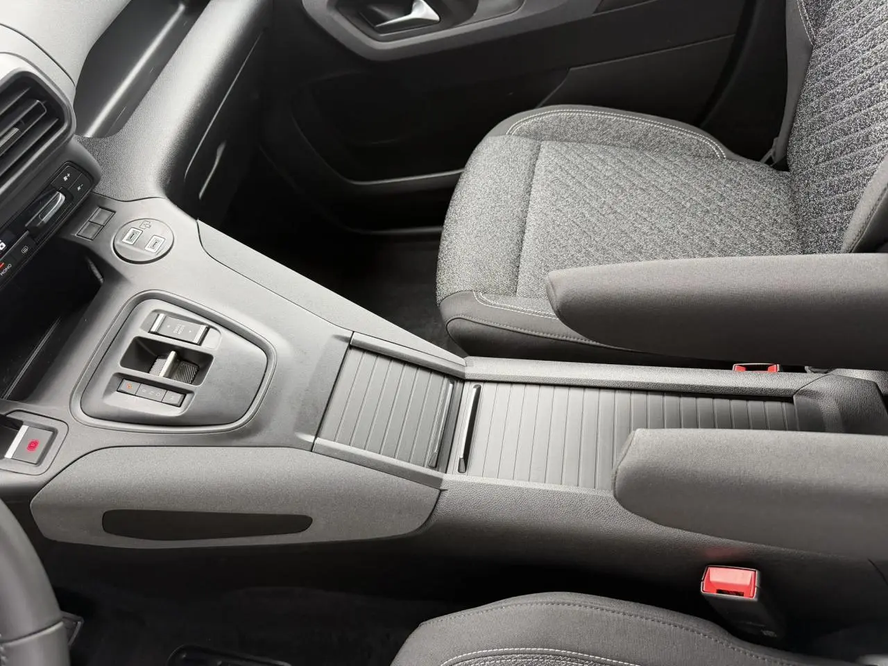 Vue intérieure centrée sur la console centrale et les sièges avant gris tissu du Peugeot Rifter 2026.