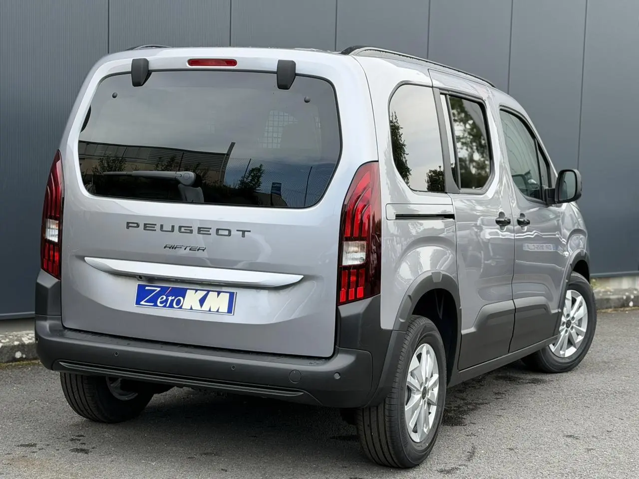 Vue 3/4 arrière droite du Peugeot Rifter gris acier 2026 avec portes coulissantes et feux arrière LED verticaux.