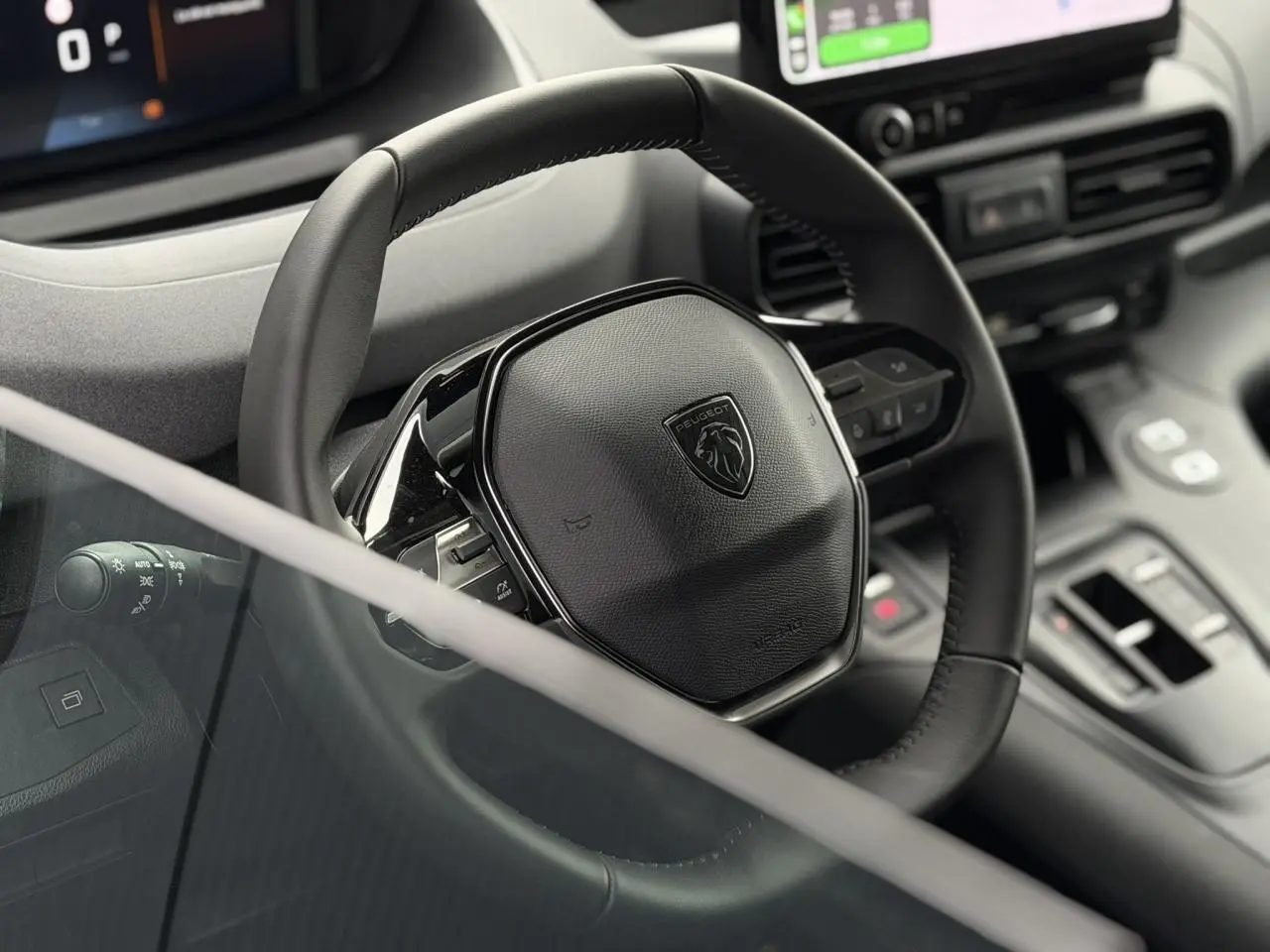 Vue rapprochée du volant cuir noir du Peugeot Rifter 2026 avec commandes intégrées et tableau de bord numérique.