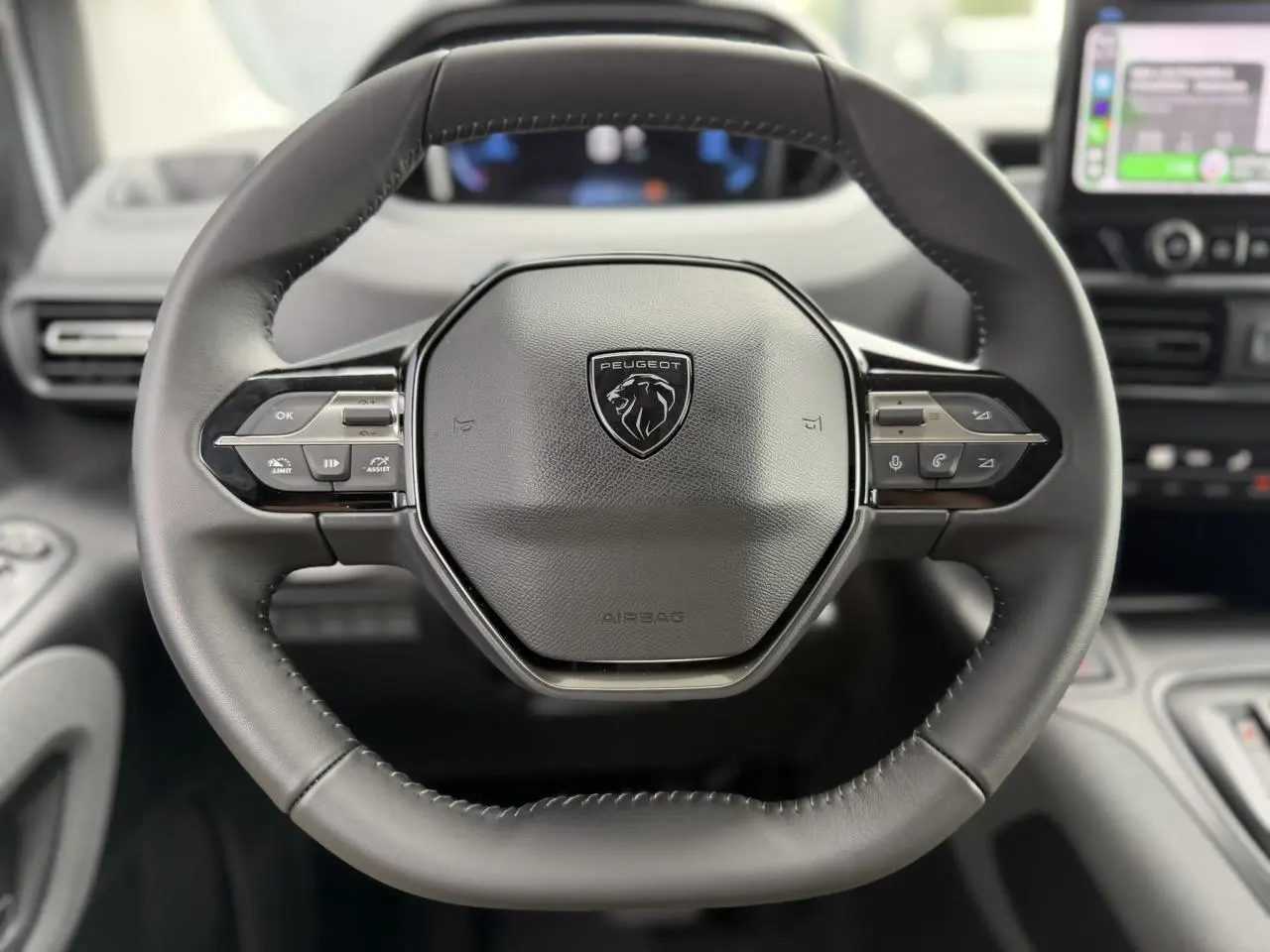 Volant cuir multifonction noir de Peugeot Rifter 2026, vue frontale centrée avec commandes intégrées et logo lion.