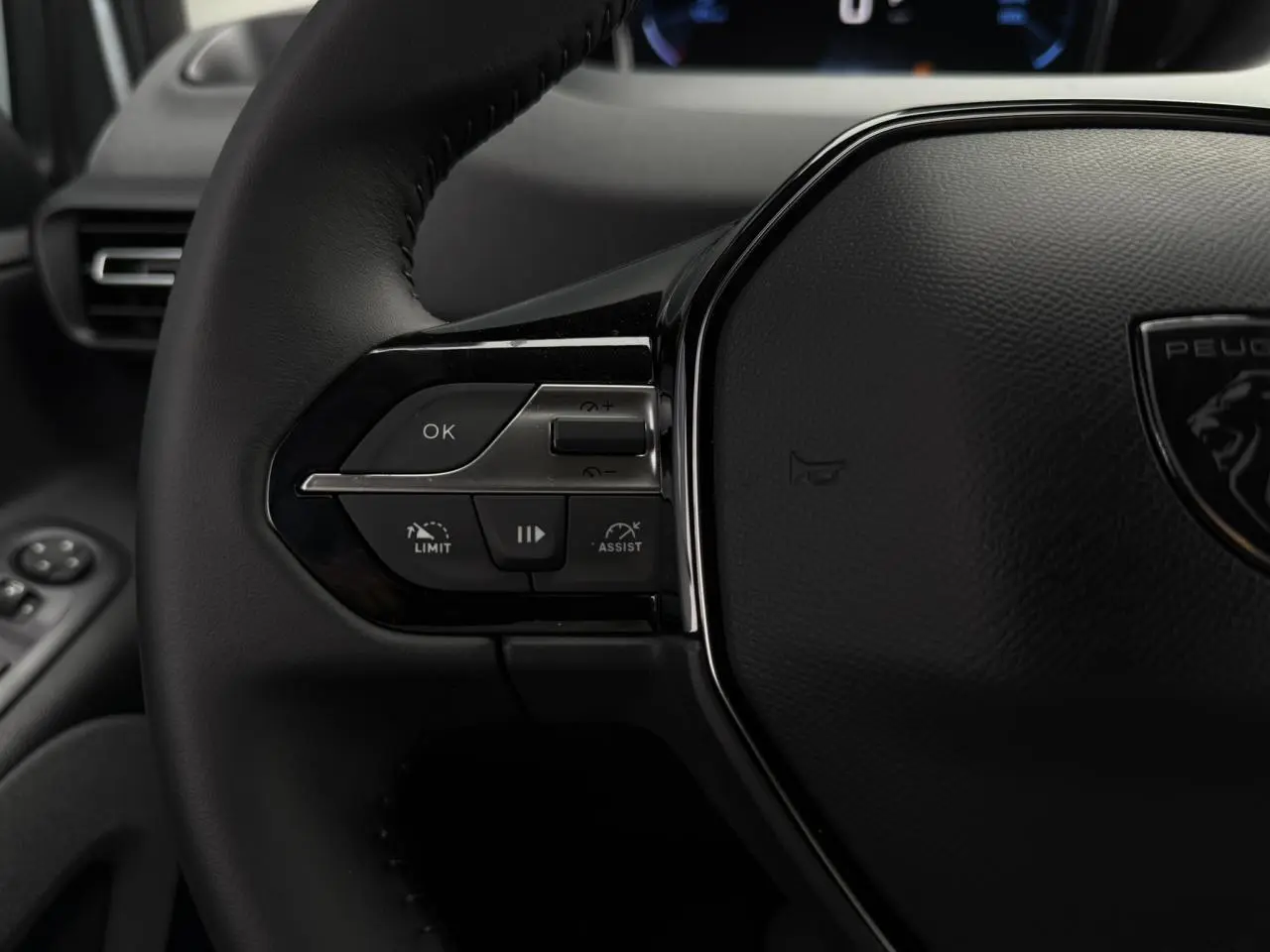 Gros plan sur le volant cuir multifonction du Peugeot Rifter 2026 avec commandes de régulateur et assistant de conduite.