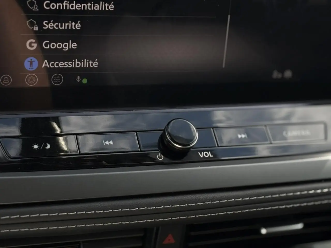 Gros plan sur la console centrale du Nissan Qashqai 2025, bouton volume et commandes tactiles sous écran tactile.