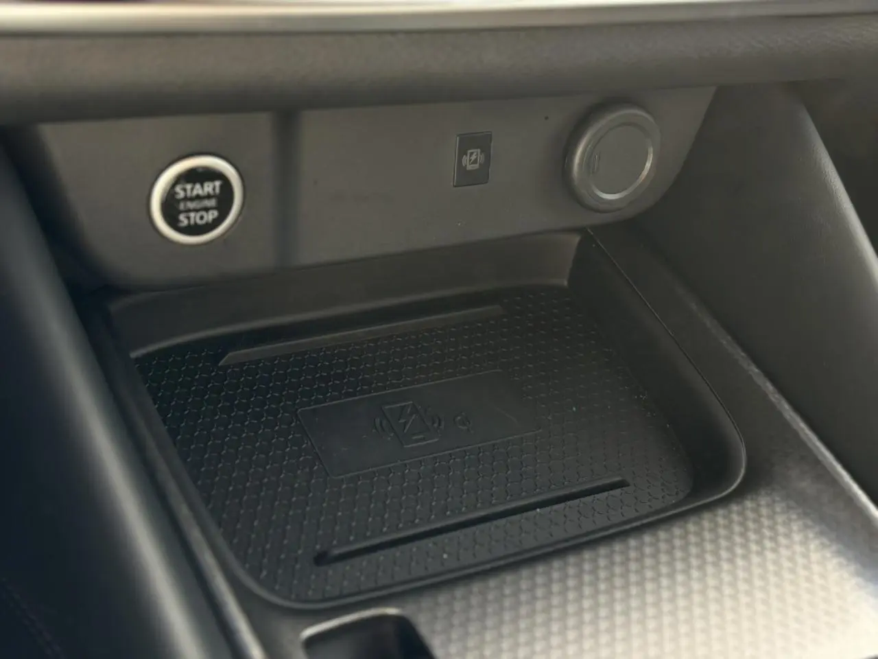 Gros plan sur le chargeur à induction noir dans l'habitacle du Nissan Qashqai gris Ceramic, avec bouton Start/Stop visible.