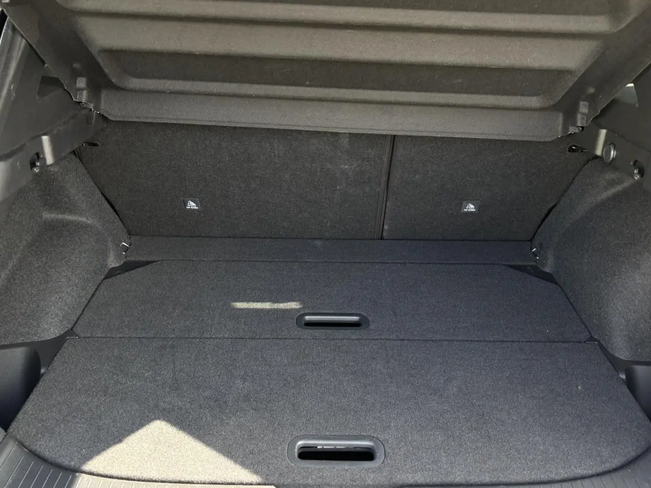 Coffre modulable ouvert du Nissan Qashqai 2025, intérieur noir avec hayon électrique visible en haut.