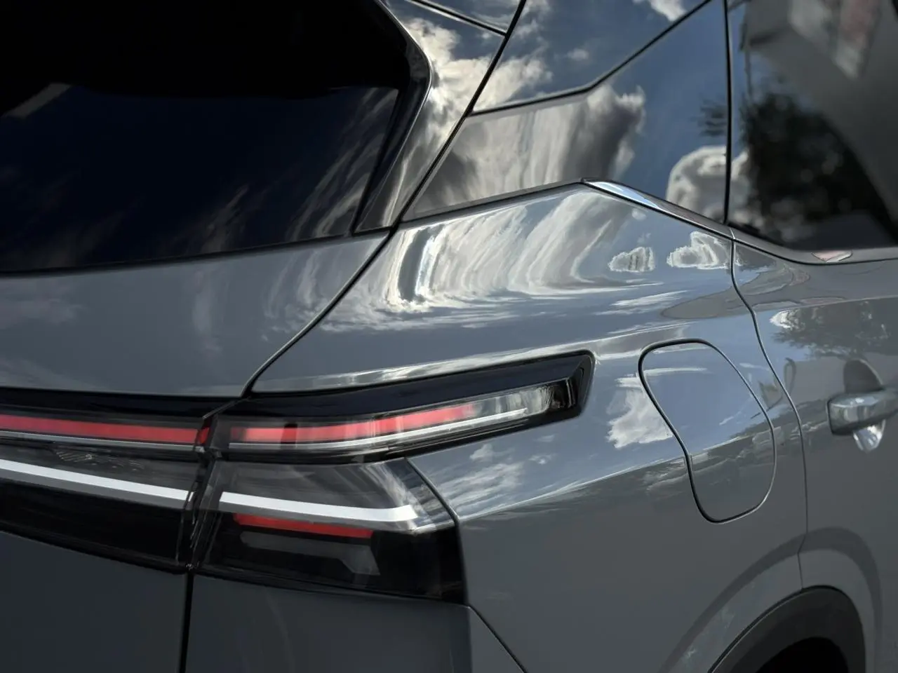 Gros plan sur le feu arrière droit et la trappe à carburant du Nissan Qashqai gris Ceramic 2025, finition N-Connecta.