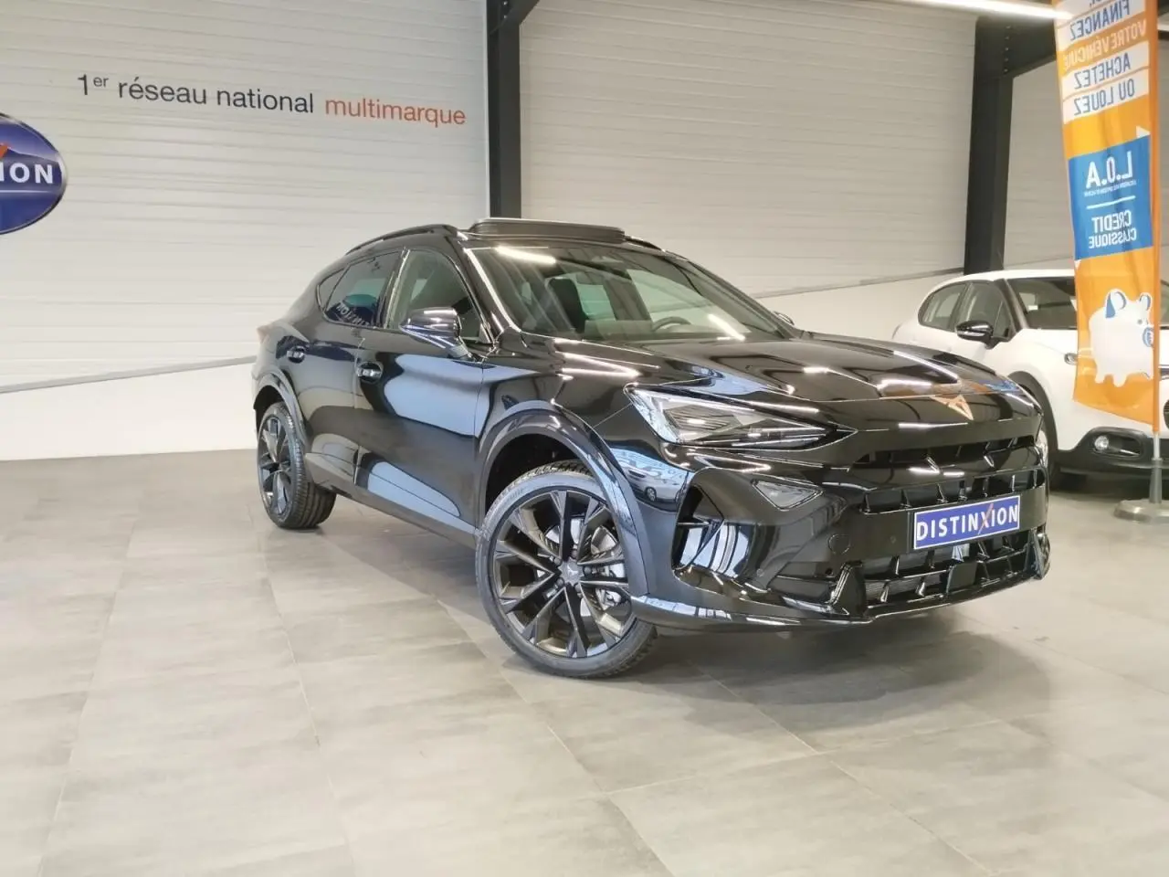 Vue 3/4 avant droite du CUPRA Formentor noir métal avec jantes alliage noires et toit ouvrant panoramique visible en intérieur showroom.