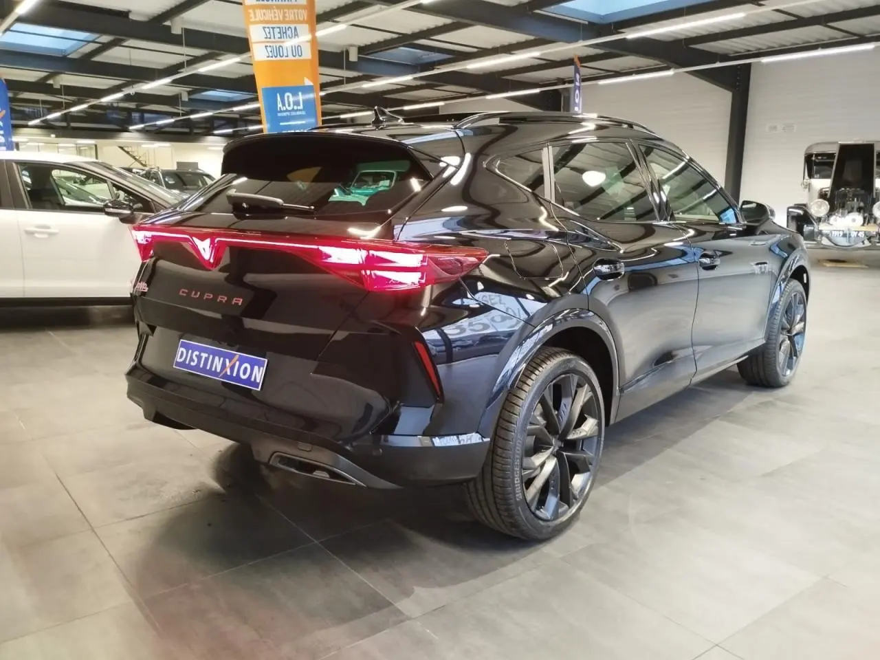 Vue 3/4 arrière droite d'une CUPRA Formentor noire métal avec feux arrière en bandeau lumineux Tri-LED et jantes alliage 19''.