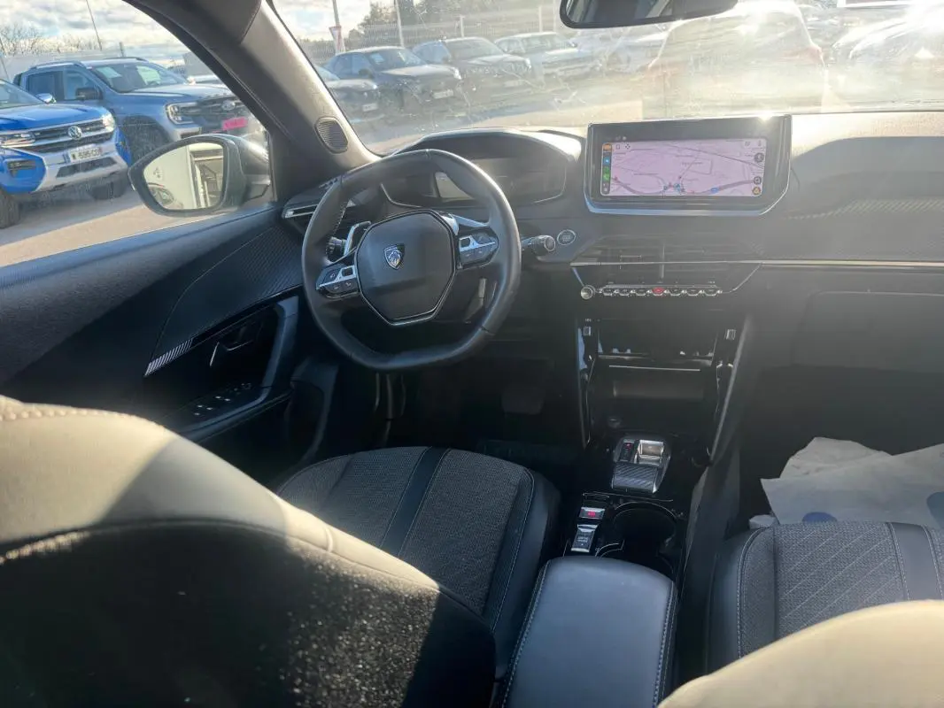 Intérieur du Peugeot 2008 Hybrid 136 Allure vu de l'arrière, montrant le volant, l'écran tactile et la console centrale noire.