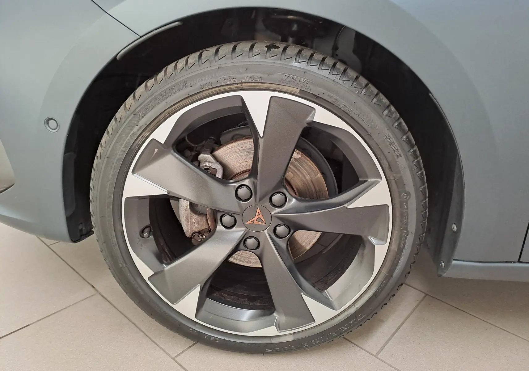 Gros plan sur la roue avant droite d'une CUPRA Leon 2024 gris magnétique mat avec jante en alliage distinctive.