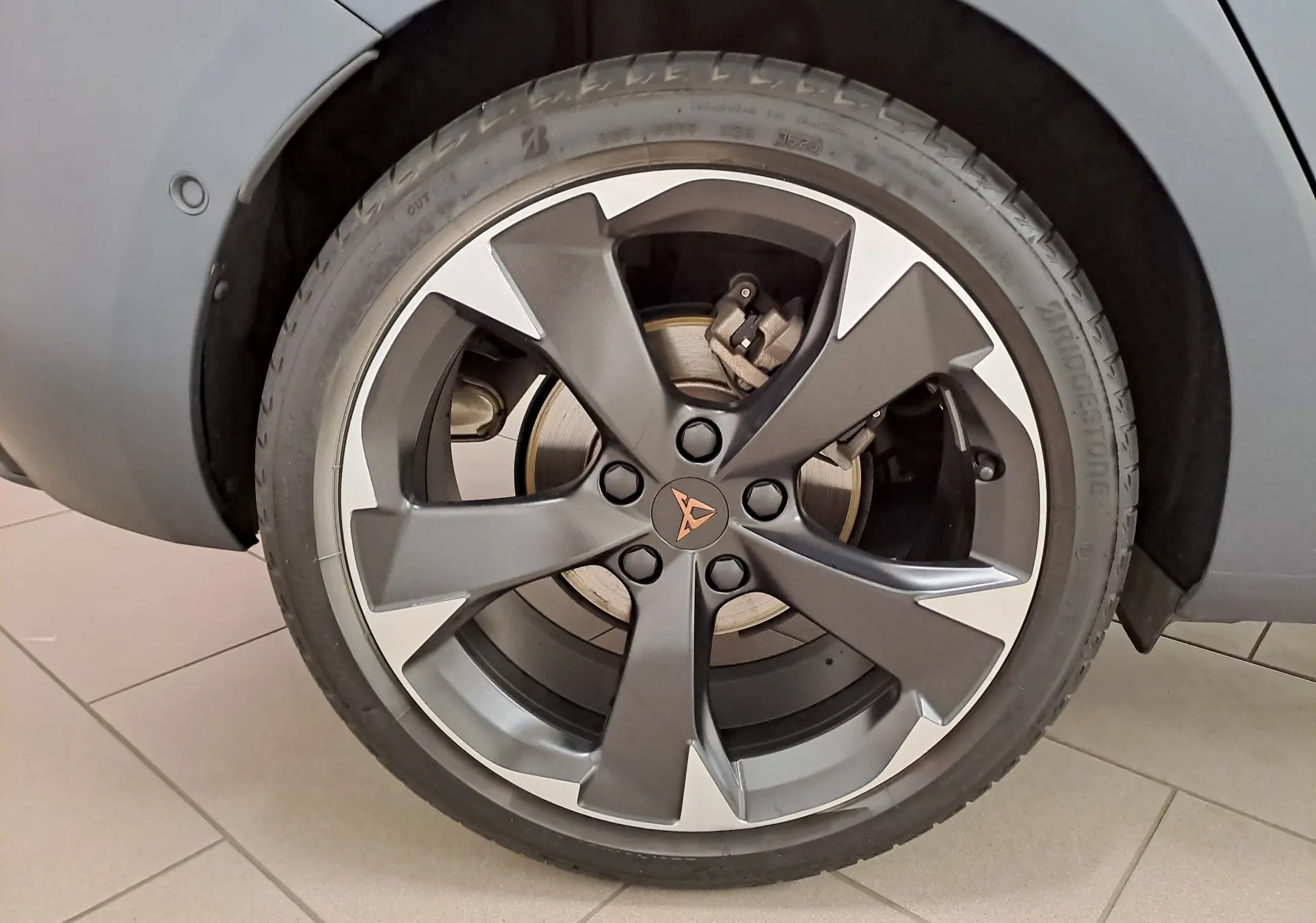 Gros plan sur la roue avant droite de la CUPRA Leon 2024 en gris magnétique mat avec jante alliage au design moderne.
