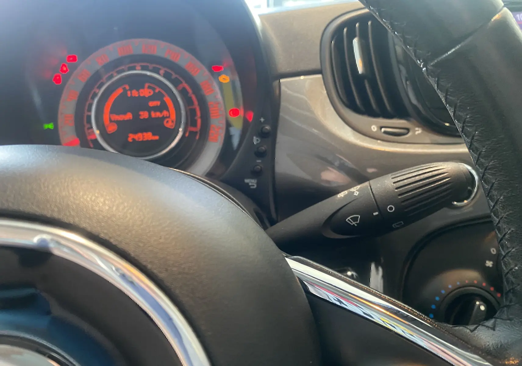 Vue rapprochée du tableau de bord gris foncé et du volant noir d'une Fiat 500 1.2 8V 69 Lounge de 2019.