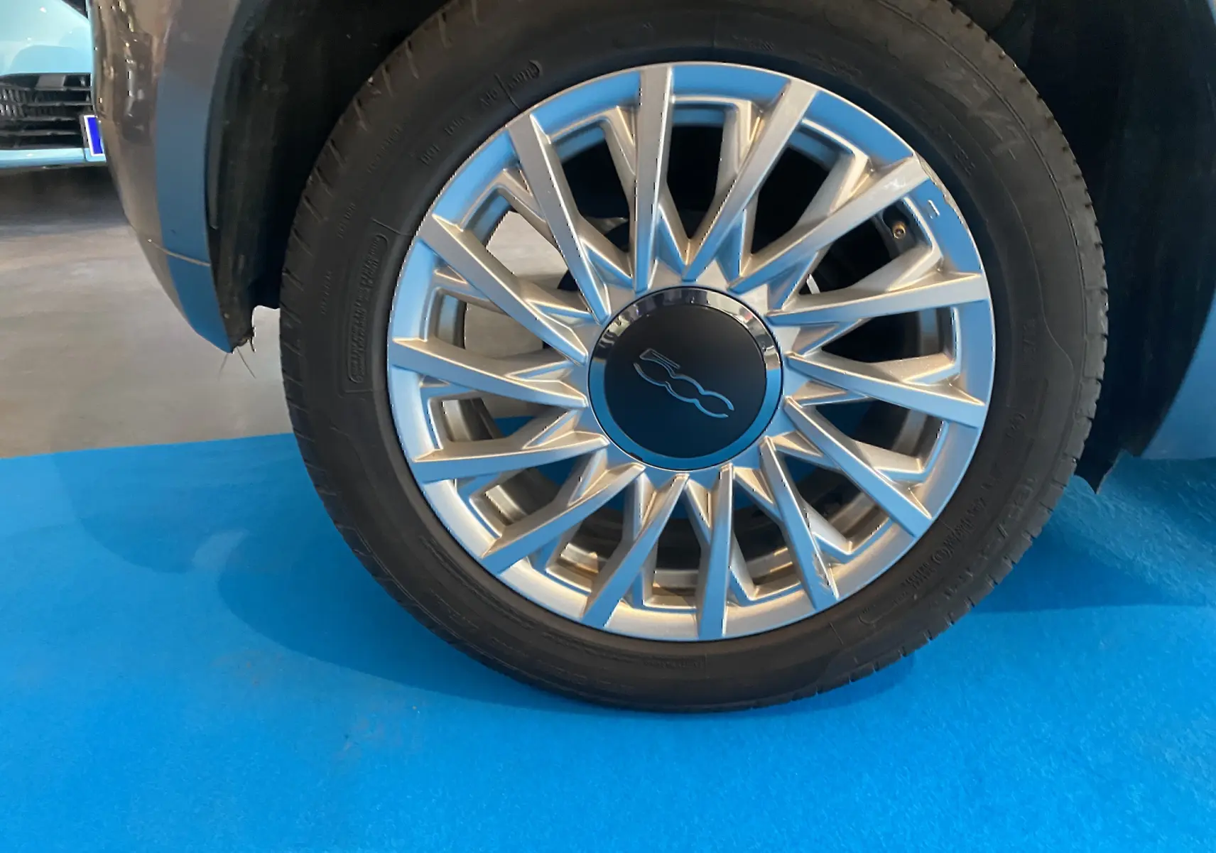 Gros plan sur la jante argentée à rayons multiples d’une FIAT 500 gris foncé, vue côté droit.