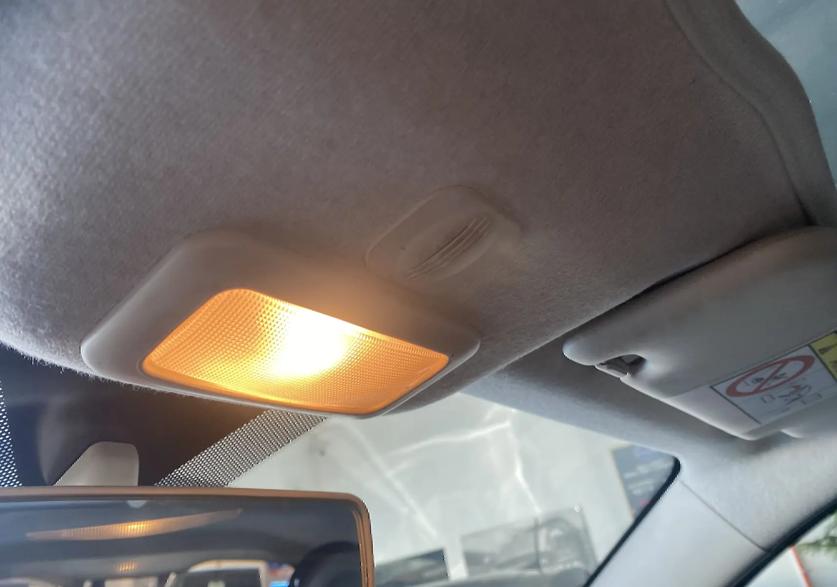 Vue intérieure du plafonnier allumé et pare-soleil côté conducteur d'une Fiat 500 gris foncé de 2019.