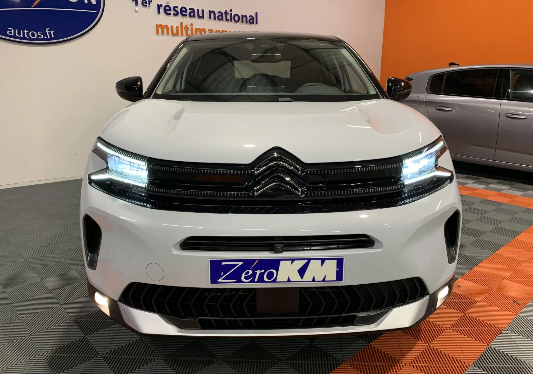 Vue avant du Citroën C5 Aircross hybride blanc 2024 avec phares LED allumés et calandre noire brillante.