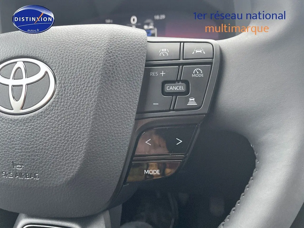 Gros plan sur le volant noir du Toyota C-HR 1.8 Hybrid 2024 avec commandes intégrées et logo Toyota visible.