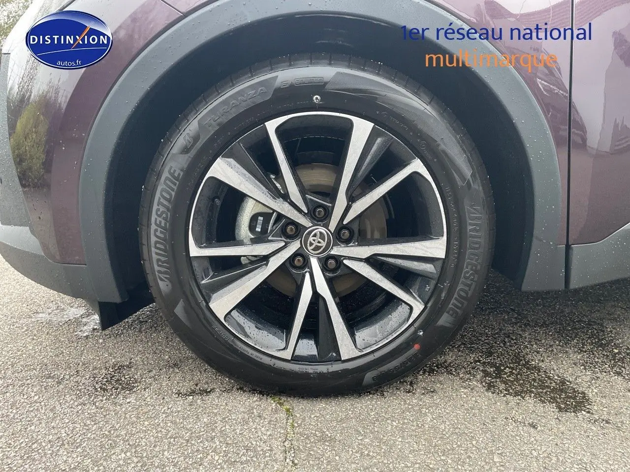 Gros plan sur la roue avant gauche du Toyota C-HR 1.8 Hybrid 2024 en couleur Améthyste métal avec jante alliage bicolore.