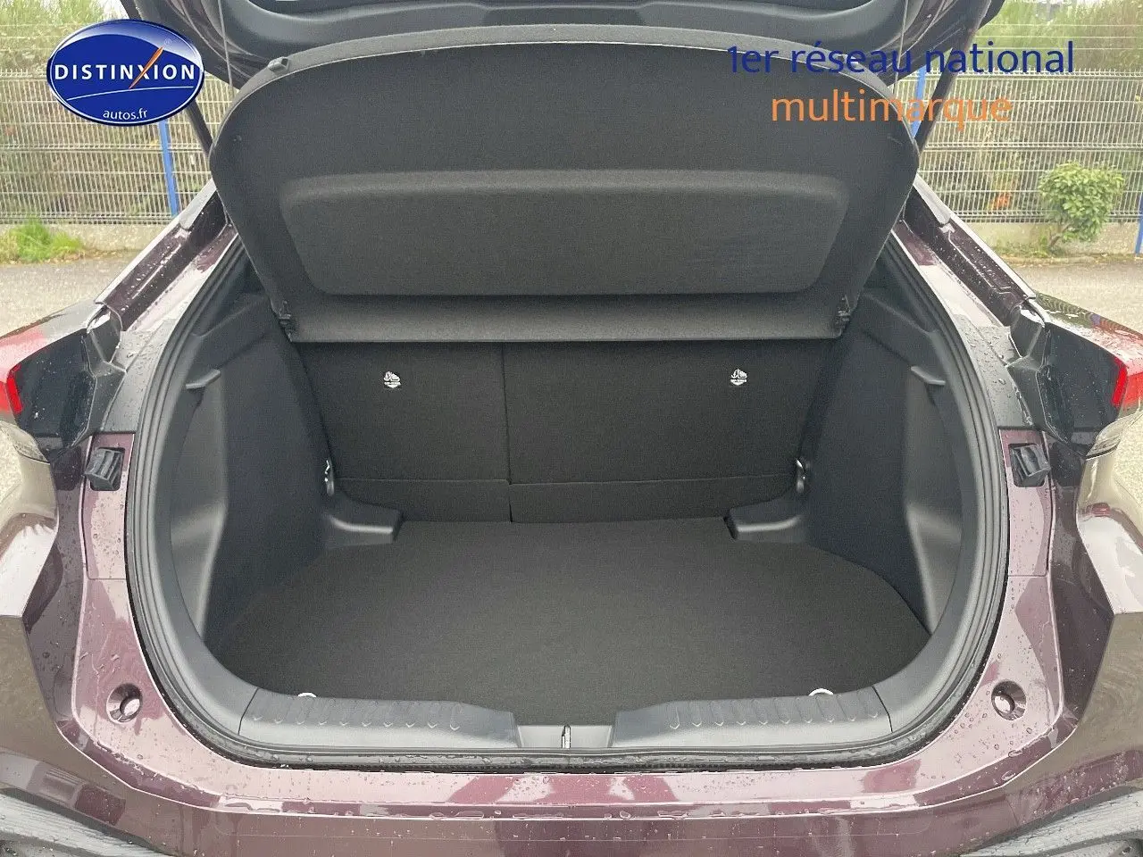 Coffre ouvert vu de l'arrière d'un Toyota C-HR 1.8 Hybrid 2024 couleur améthyste métal, intérieur noir spacieux et propre.