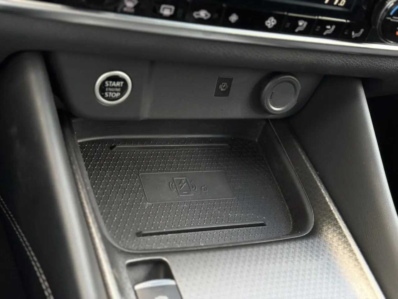 Gros plan sur la zone de recharge sans fil et bouton Start/Stop dans l'habitacle noir du Nissan Qashqai 2025.