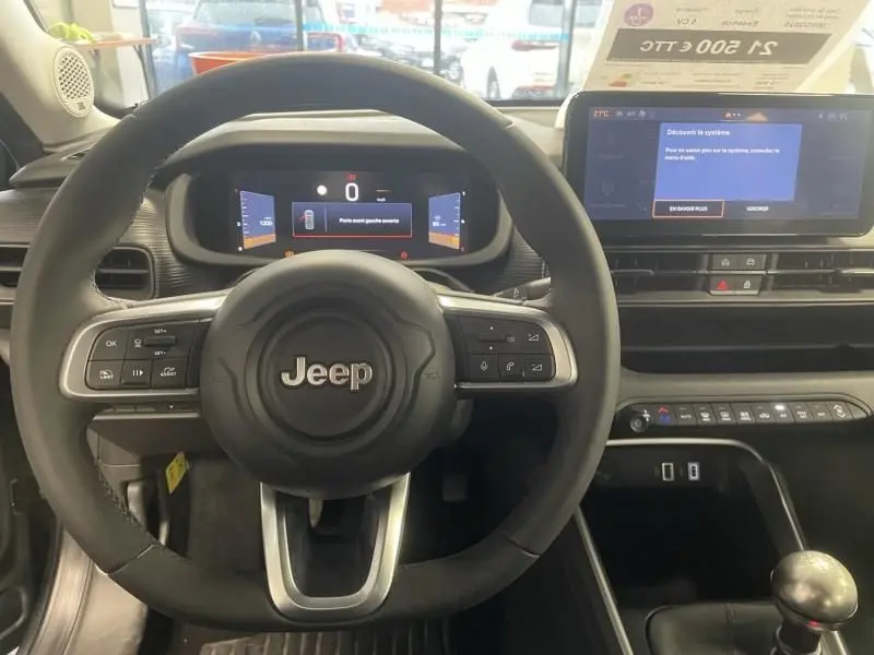 Vue intérieure centrée sur le volant Jeep noir et le tableau de bord numérique du Jeep Avenger 2025 essence boîte manuelle.