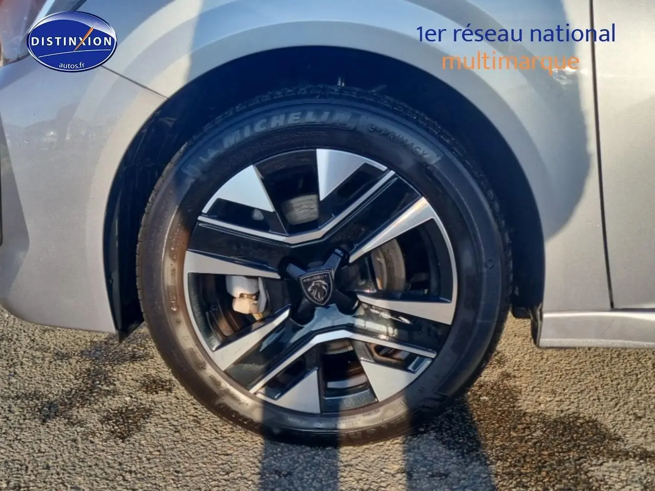 Gros plan sur la roue avant droite de la Peugeot 208 gris artense avec jante alu bicolore.