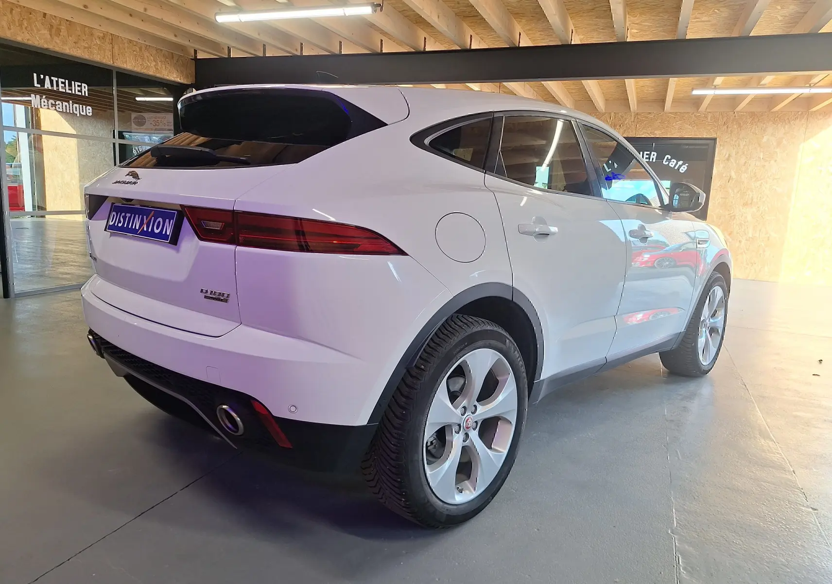 Jaguar E-PACE blanc en 3/4 arrière droit, avec feux arrière LED et jantes alliage cinq branches.