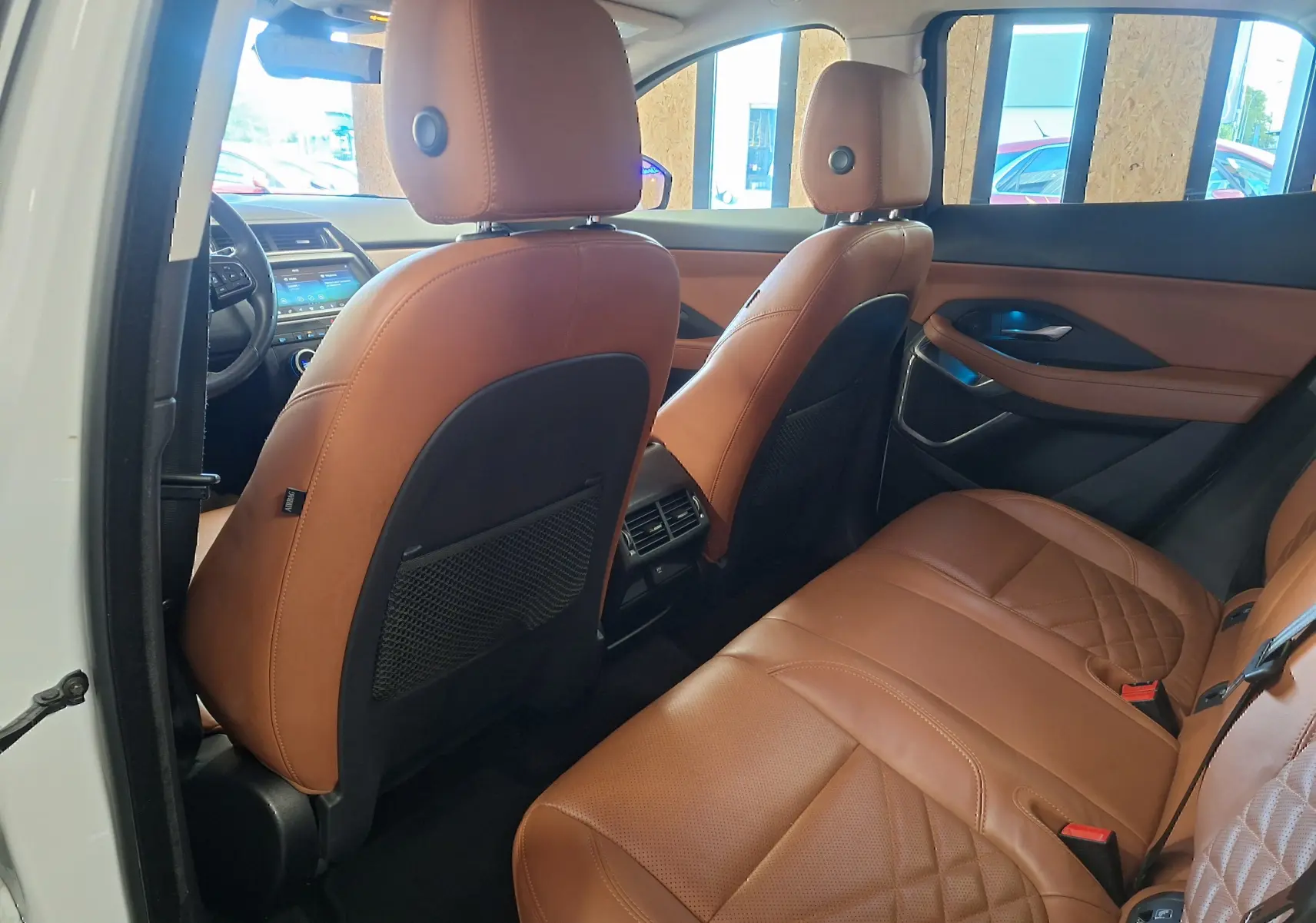 Vue intérieure arrière droite du Jaguar E-PACE blanc 2019 avec sièges en cuir marron et détails de finition raffinée.