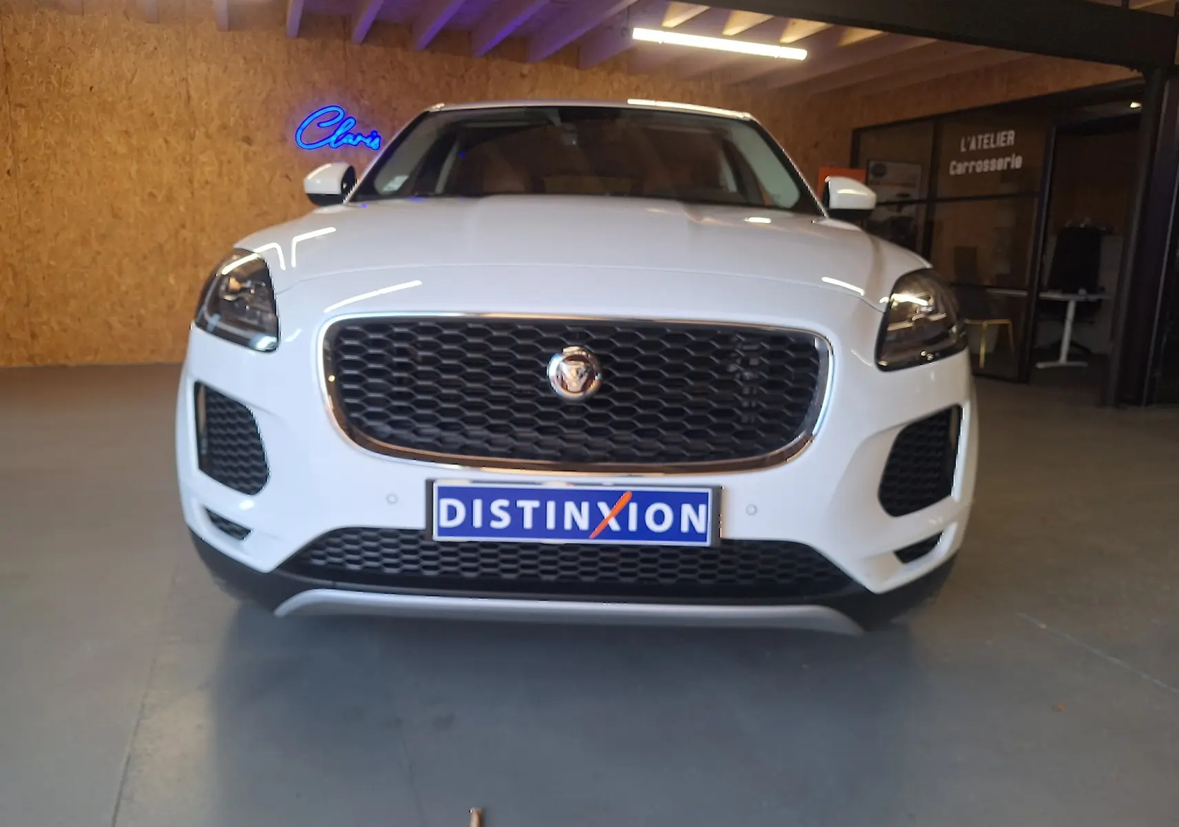 Vue frontale d'un Jaguar E-PACE blanc 2019 avec calandre noire et phares LED allumés en intérieur.