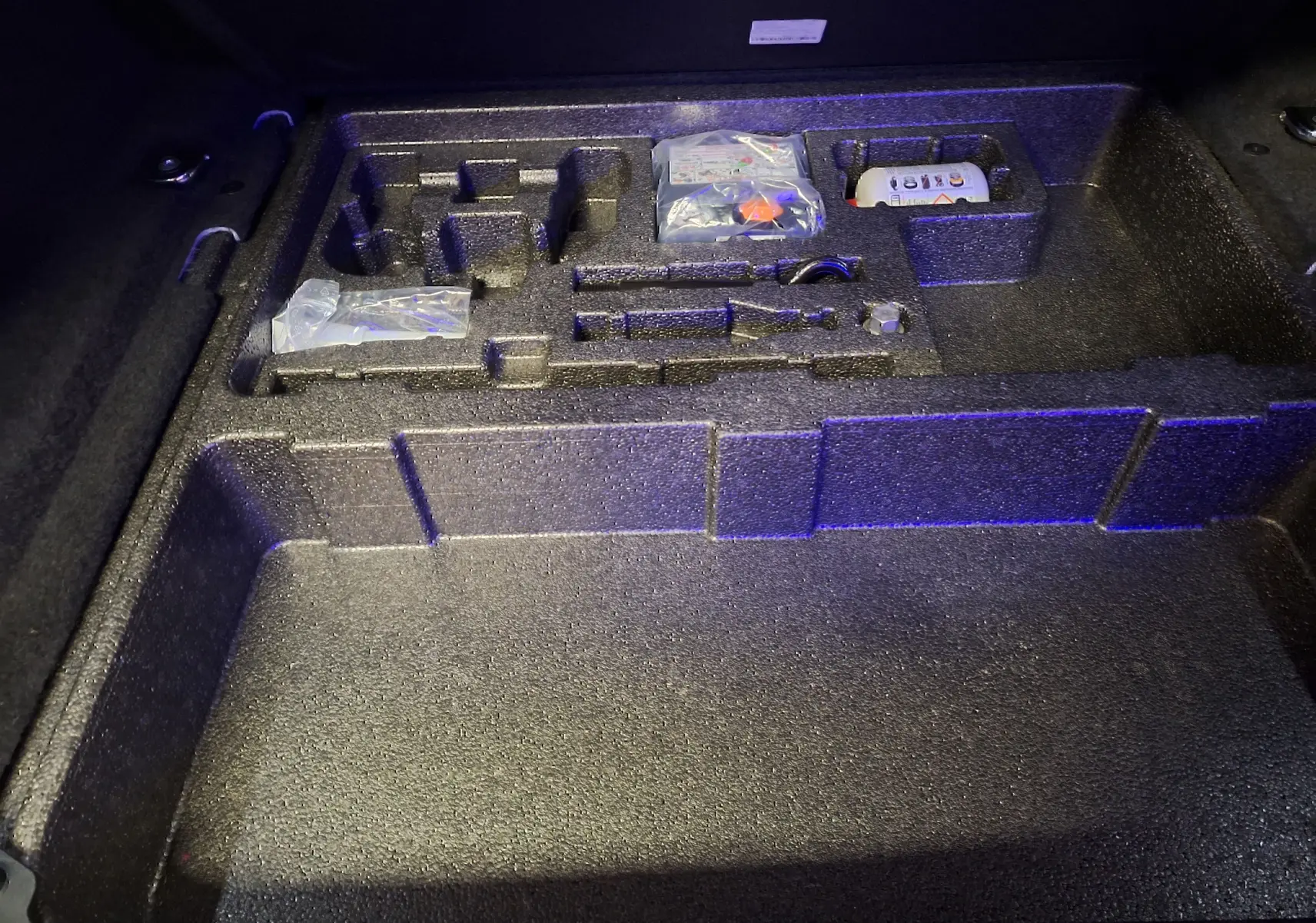 Rangement en mousse noire sous le coffre du Jaguar E-PACE 2019, compartiments pour outils et accessoires.