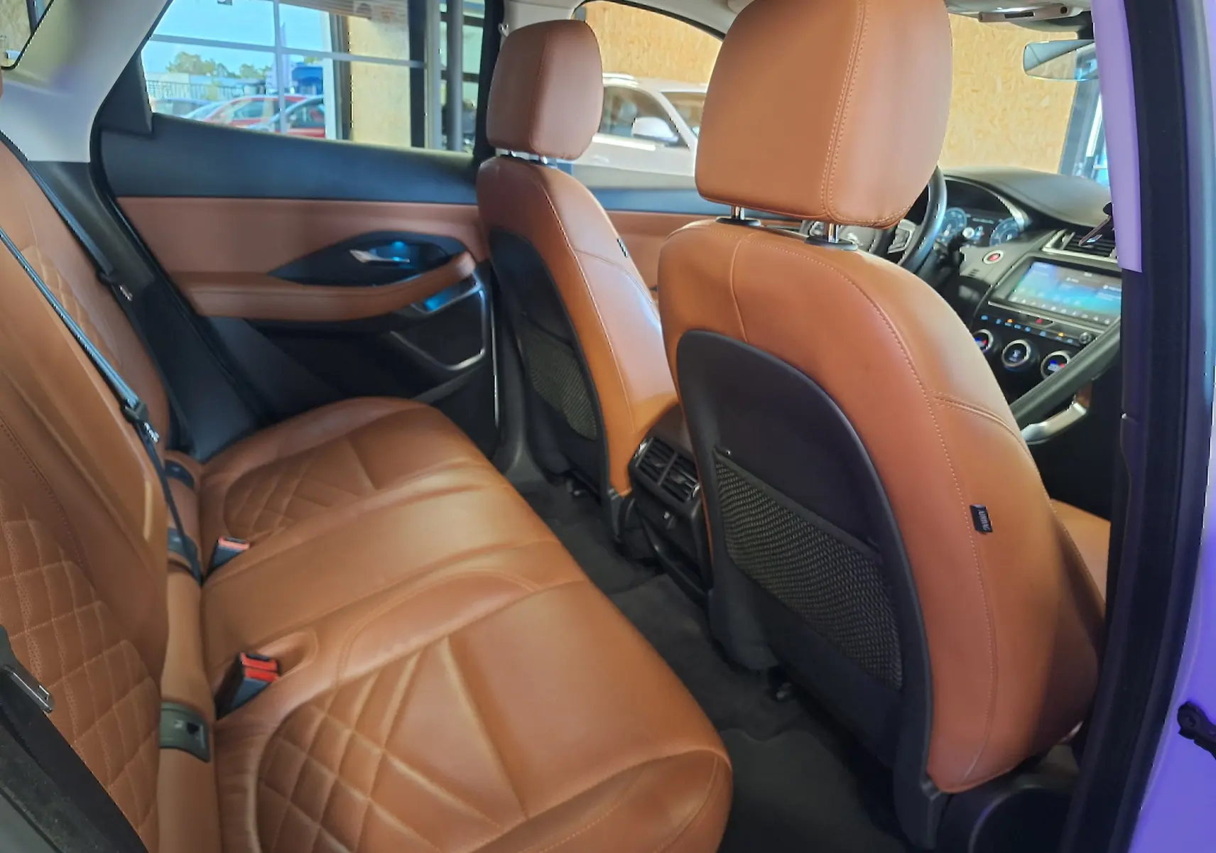 Vue intérieure arrière droite du Jaguar E-PACE 2019 blanc, sièges en cuir marron avec surpiqûres élégantes.