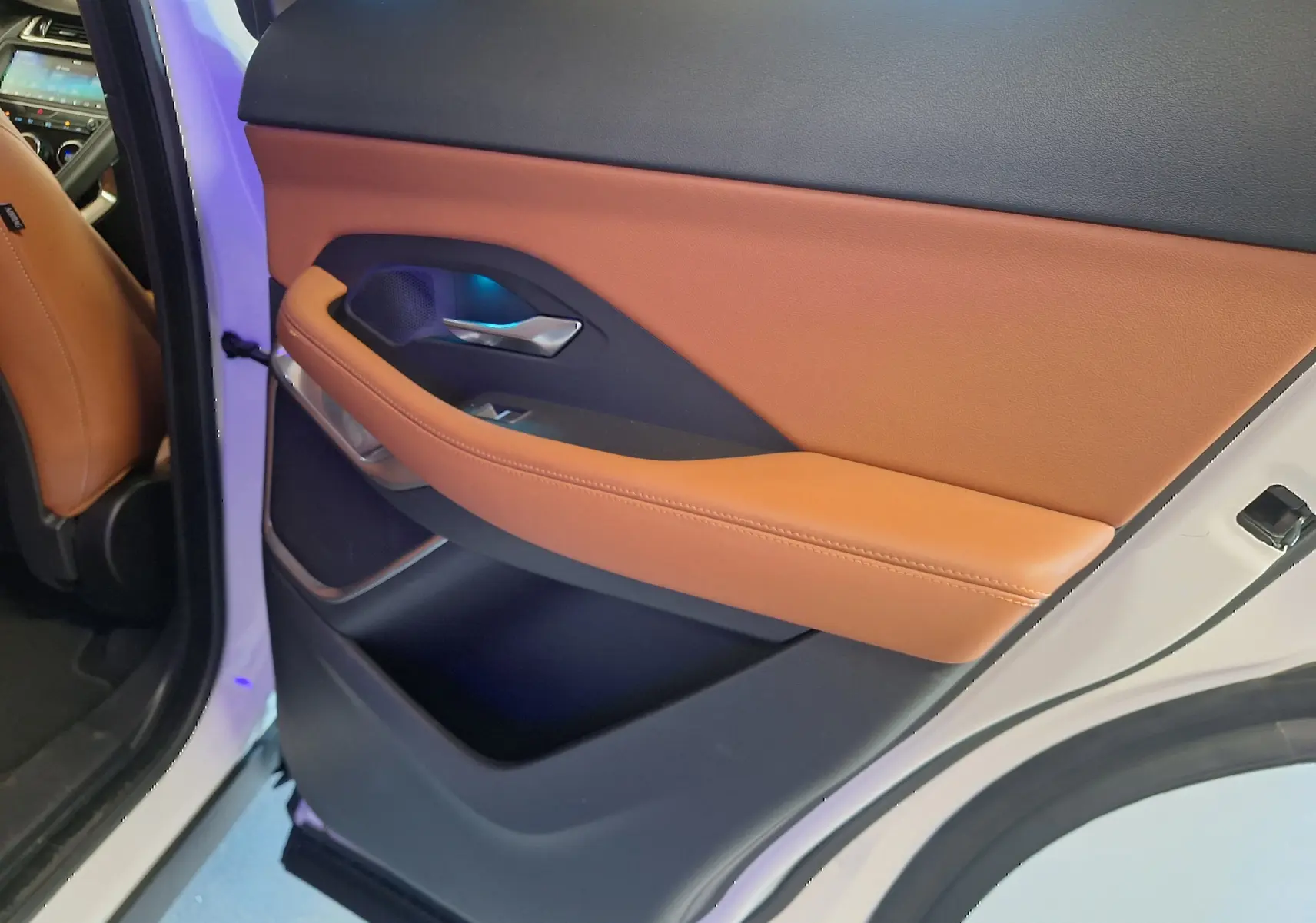 Gros plan sur la garniture cuir marron et noire de la porte arrière gauche du Jaguar E-PACE blanc 2019.