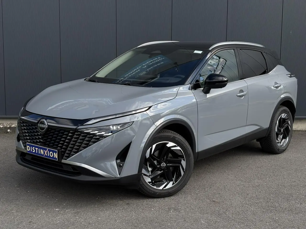 Nissan Qashqai gris Ceramic en 3/4 avant droit, avec calandre noire et jantes alliage 18 pouces distinctives.