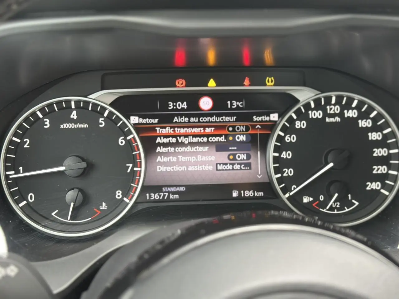 Tableau de bord du Nissan Qashqai 2024 montrant l'écran d'aide au conducteur et les compteurs de vitesse et régime moteur.