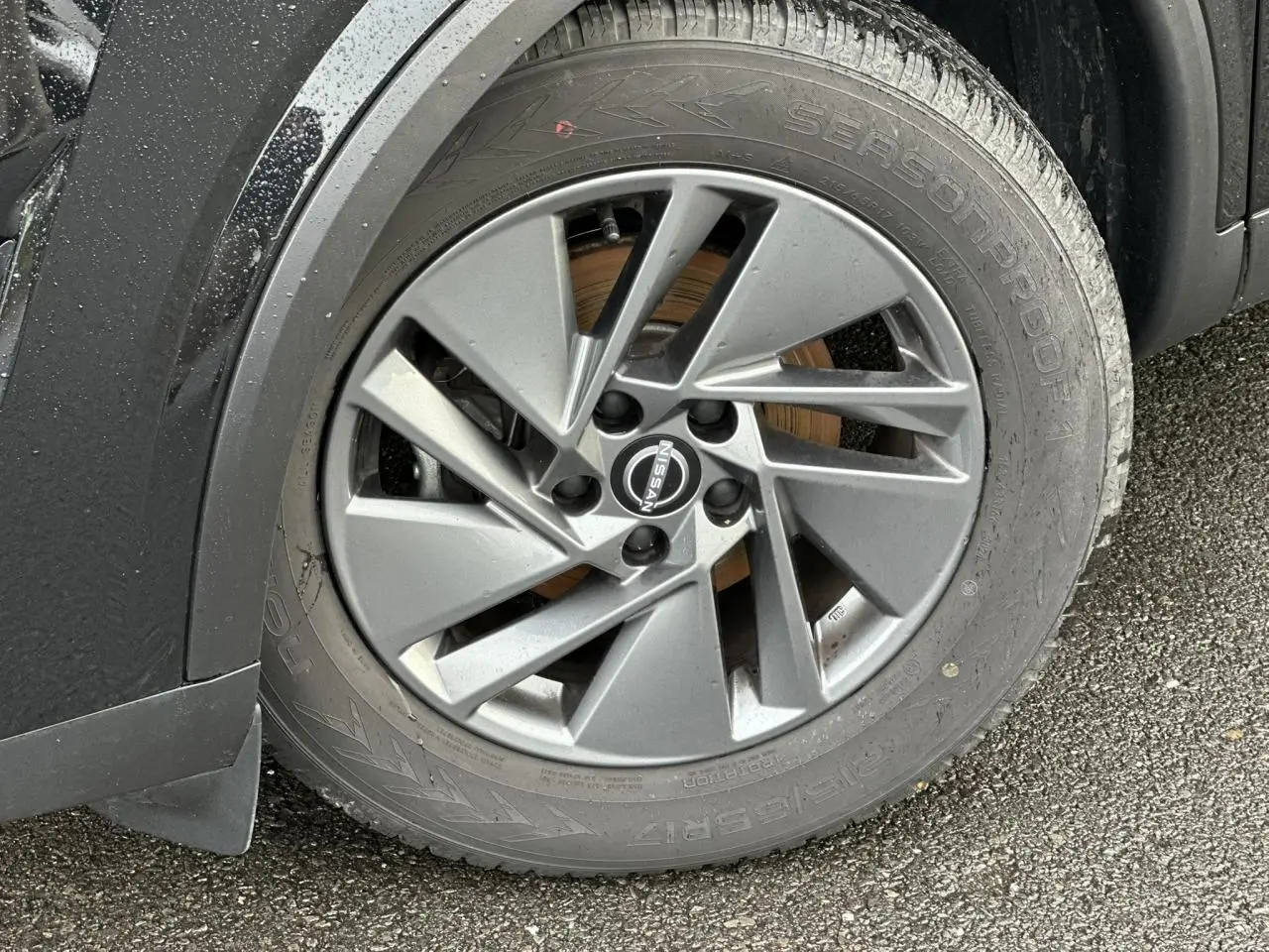 Gros plan sur la jante alliage 17 pouces grise du Nissan Qashqai noir nacré, côté avant gauche, avec logo Nissan visible.