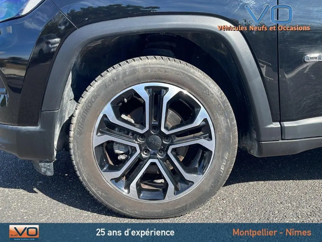 Gros plan sur la roue avant gauche noire du Jeep Compass 2023 avec jante alliage 18 pouces et logo Jeep au centre.