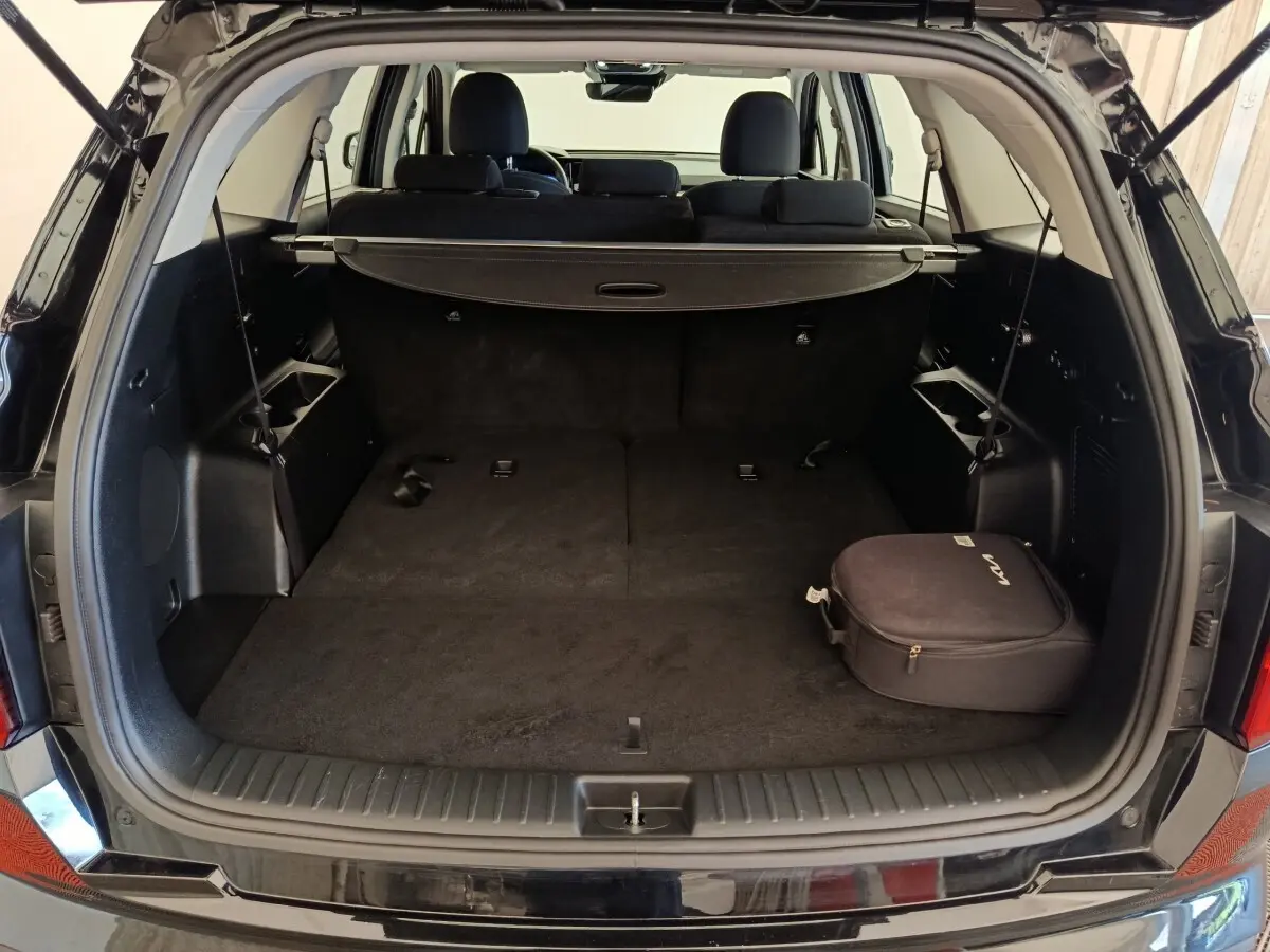 Coffre ouvert du Kia Sorento noir 2023 vu de l'arrière, avec plancher plat et cache-bagages déployé.