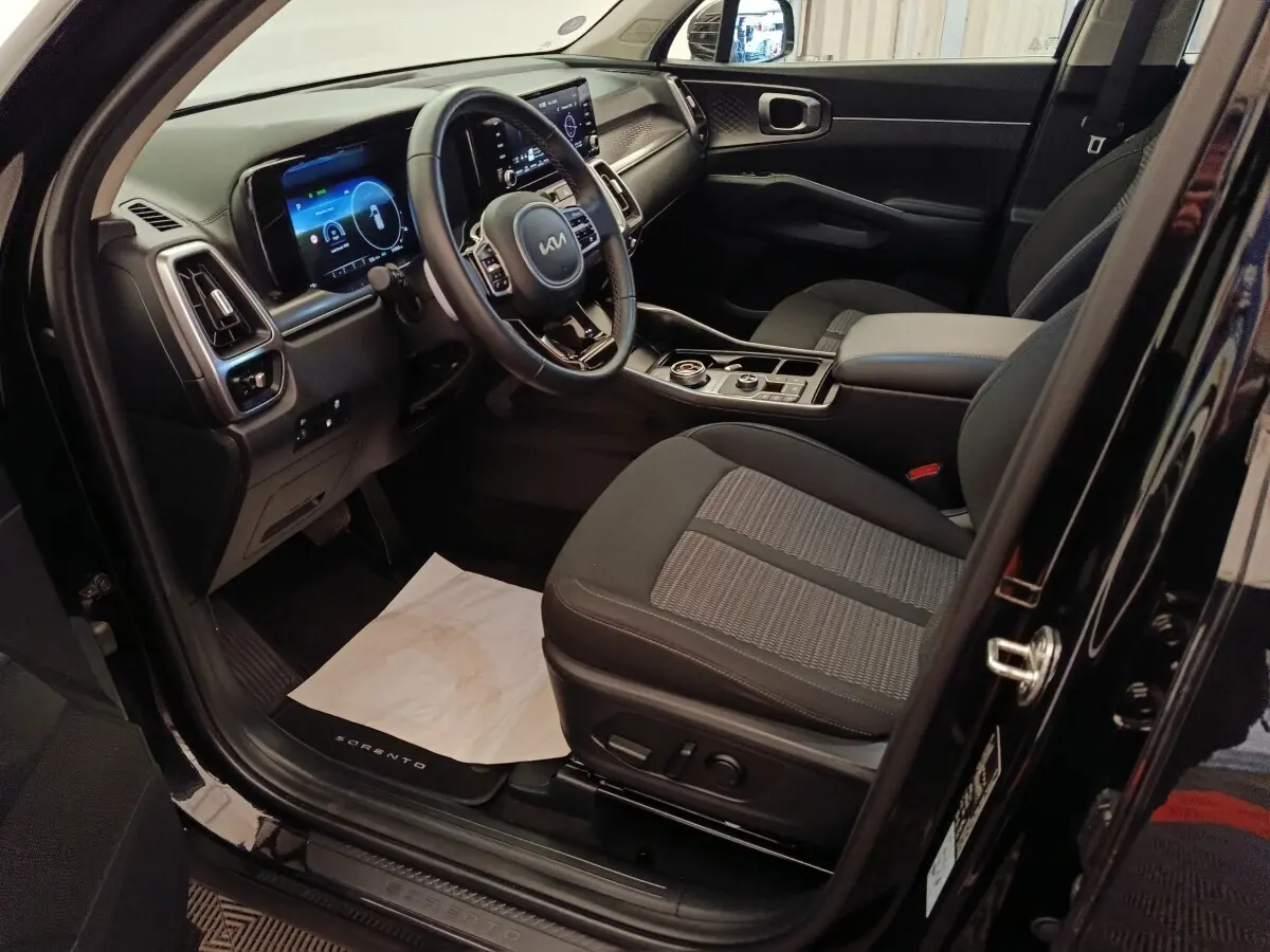 Vue intérieure côté conducteur du Kia Sorento noir 2023, avec tableau de bord digital et sièges tissu gris.