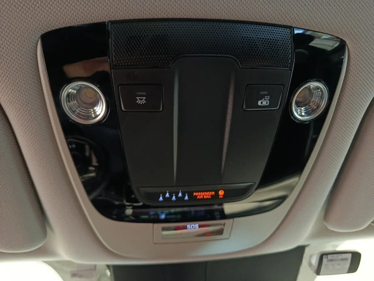 Vue en contre-plongée du plafonnier noir avec éclairages et indicateur airbag passager du Kia Sorento 2023 hybride.
